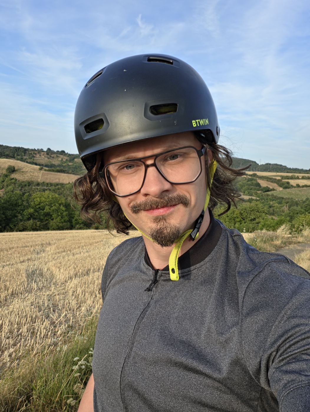 Selfie mit Helm vor Stoppelfeldern im Abendlicht