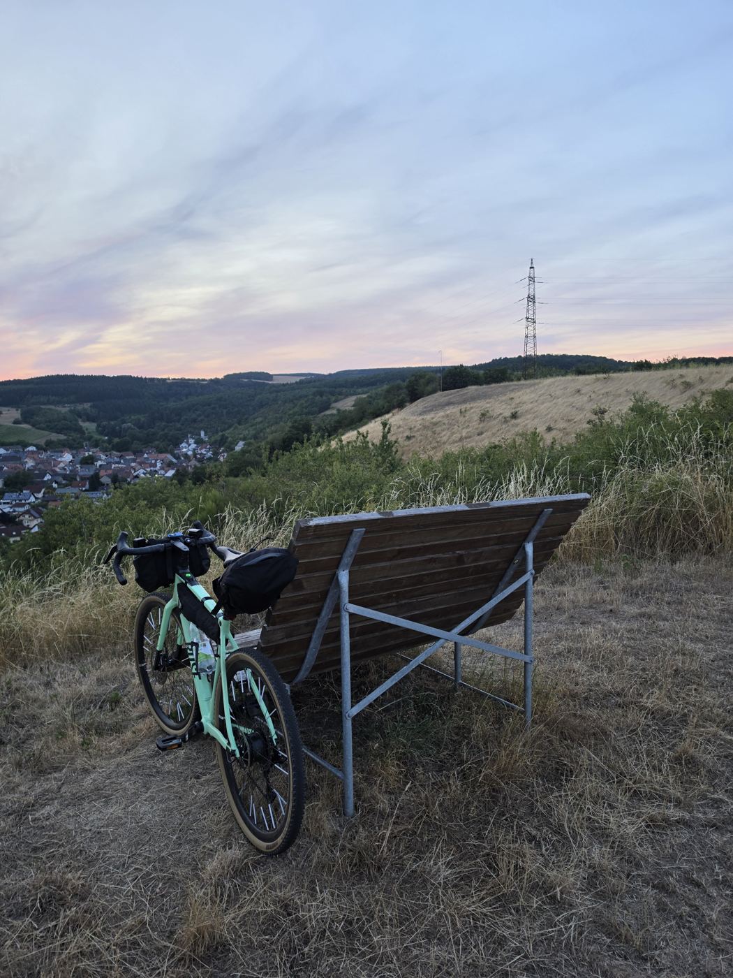 Das ROSE lehnt an der Himmelsliege, dahinter Abendrot über dem Tal mit Dorf