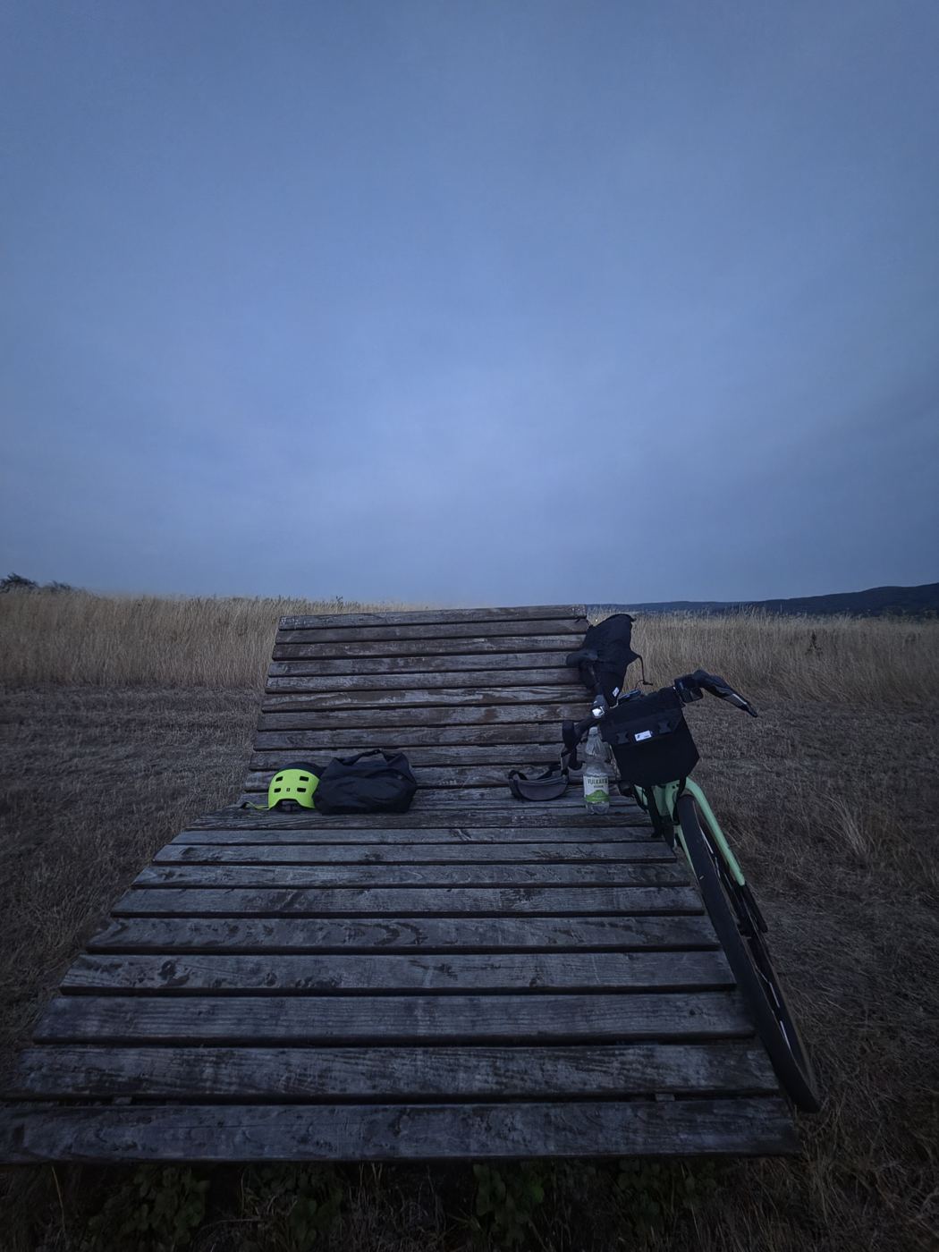 Die Himmelsliege in der blauen Stunde mit Helm, Taschen und Wasserflasche, das Rad am Kopfende