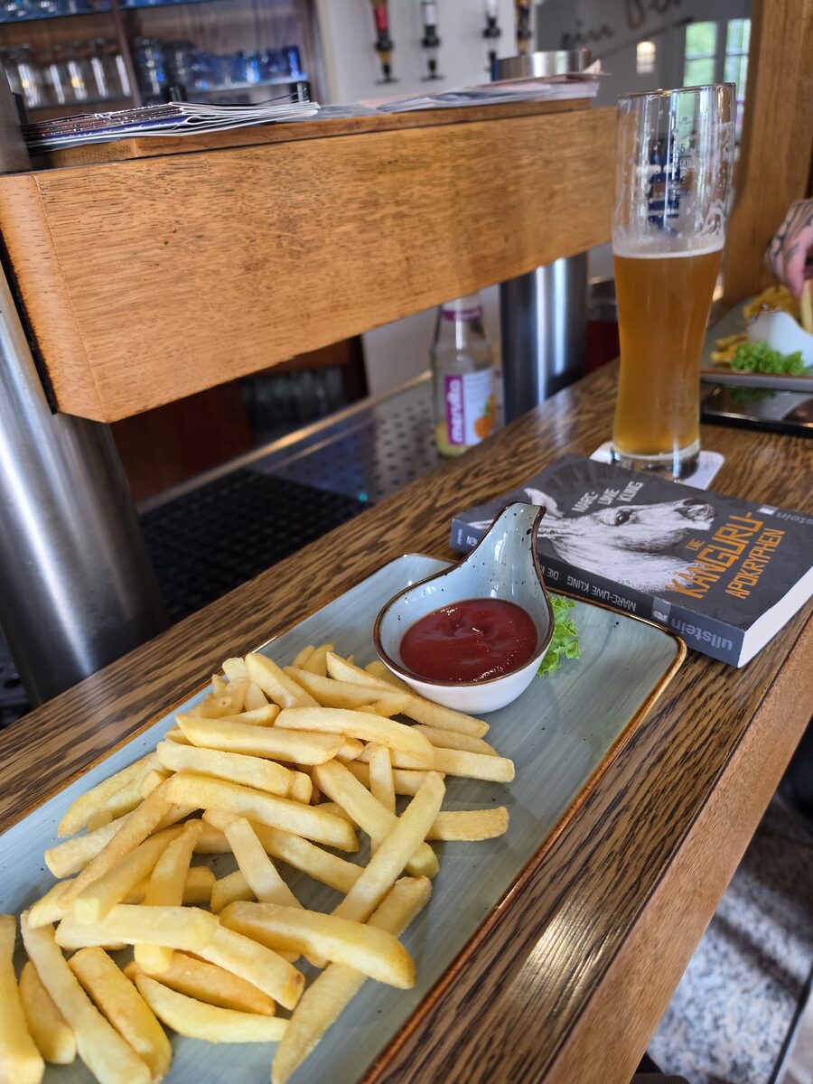 Pommes mit Ketchup, ein alkoholfreies Kirner Weizen und das Känguru-Buch auf dem Tresen