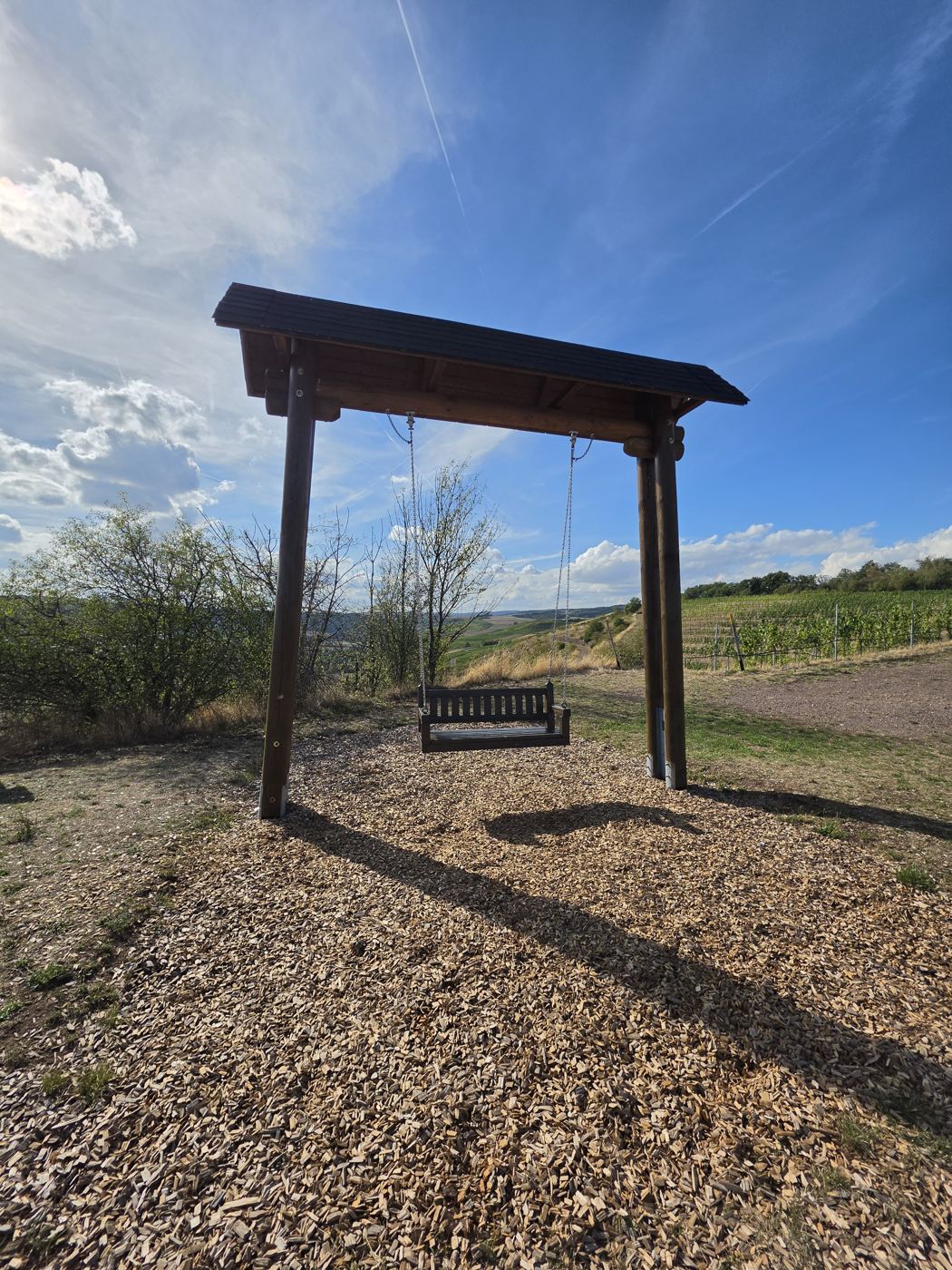 Hollywoodschaukel unter Holzportal am Aussichtspunkt mit Blick über die Weinberge